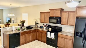 A modern kitchen with wooden cabinets, a black refrigerator, a microwave, a stove, and a dishwasher. - Quiet and Beautiful House in a WONDERFUL location near 2 Lakes and Charlotte! (Huntersville)