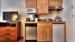 A compact kitchenette with wooden cabinets, a microwave, a coffee maker, a toaster, a kettle, and a dishwasher. - Grand Timber Lodge  Ski in/Ski out --two bedroom kitchenette (Breckenridge)