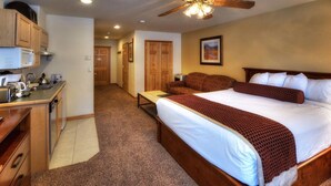 A hotel room with a large bed, a desk with a microwave, a chair, and a ceiling fan. - Grand Timber Lodge  Ski in/Ski out --two bedroom kitchenette (Breckenridge)