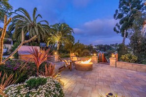 Une terrasse extérieure dotée d’un foyer, de sièges et offrant une vue sur le paysage environnant.