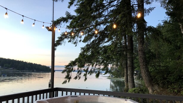 Un bain à remous sur une terrasse, avec vue sur un lac et des arbres.