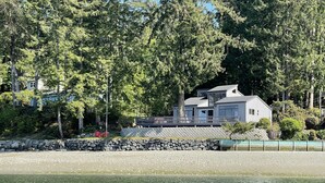 Une maison au bord du lac, dotée d’un mur en pierre et d’une terrasse offrant une vue sur l’eau.