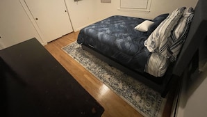 Una camera da letto con un letto, una TV a muro, una porta e una finestra con persiane.