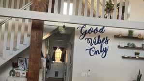 A spacious loft with a high ceiling, a wooden staircase, and a 'Good Vibes Only' wall sign. - ReTreat yourself with this sunny A-frame experience (delta)