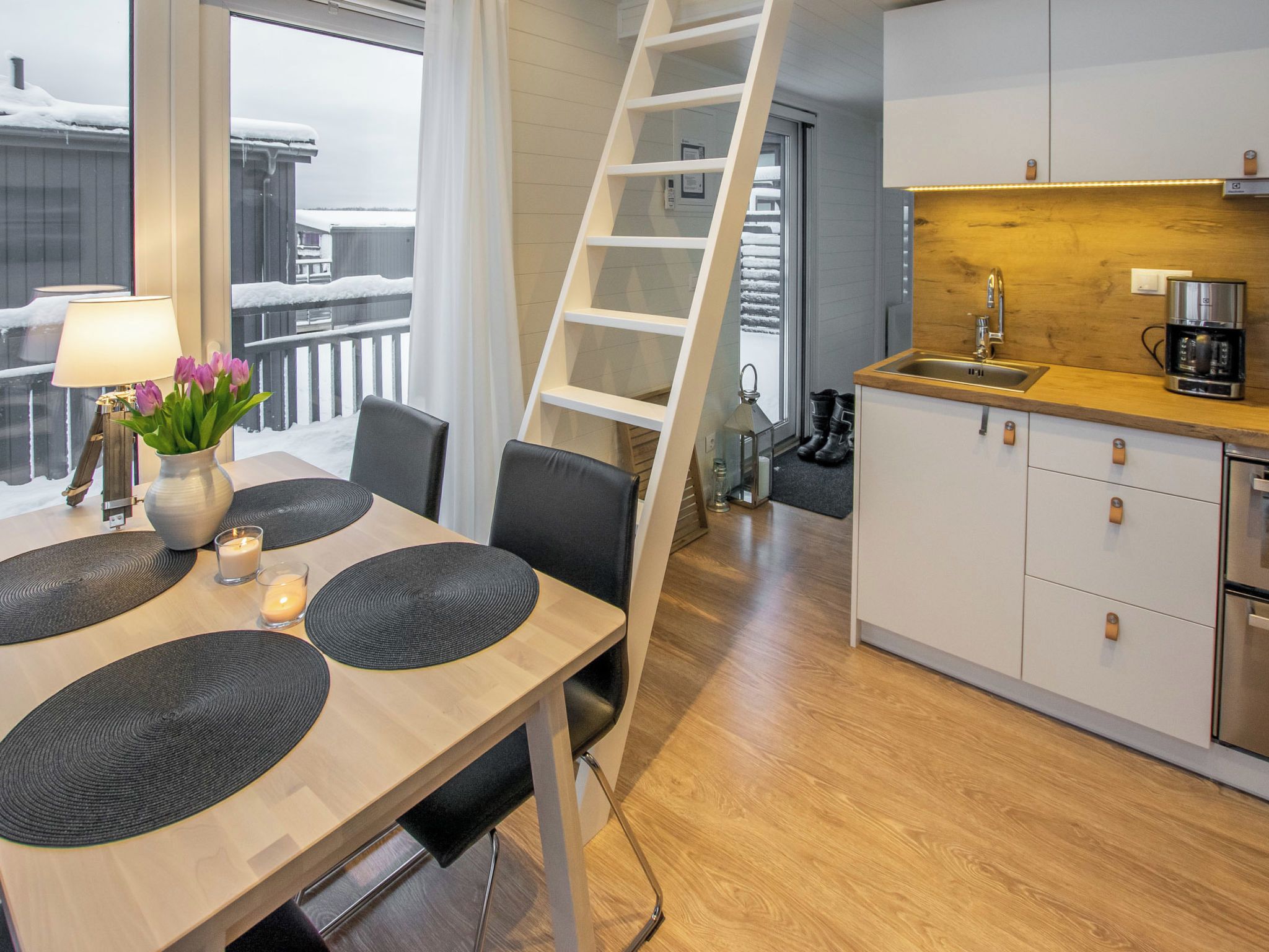 Una cocina moderna con encimera de madera, armarios blancos y un lavabo de acero inoxidable.