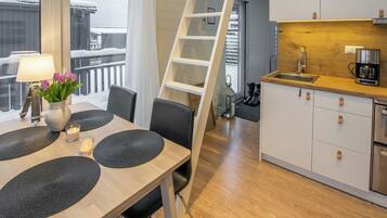 Una cocina moderna con encimera de madera, armarios blancos y un lavabo de acero inoxidable.