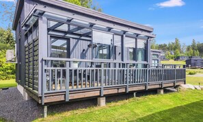 Un bâtiment moderne doté de grandes fenêtres, d’un balcon et d’une terrasse en bois.