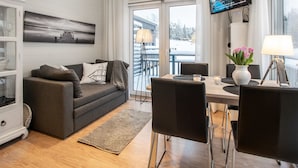 A modern living room with a grey sofa, black chairs, a wooden dining table, and a TV mounted on the wall. - Willa anna b by Interhome (Kemiönsaari)
