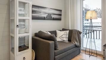 A modern living room with a grey sofa, a white cabinet, and a large window with a view of a snowy landscape.