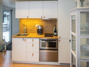 Une cuisine compacte dotée d’un plan de travail en bois, d’appareils électroménagers en acier inoxydable et d’un meuble vitré.