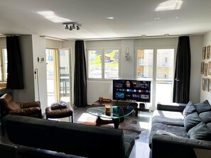A living room with a sofa, armchair, coffee table, and a flat-screen TV.