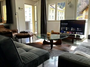 A modern living room with a glass coffee table, leather sofas, and a flat-screen TV displaying a music service. - Gerschnistrasse 10 Appartement/Fewo 6-Bettwohnung by Interhome (Engelberg)