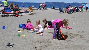 Uma praia com pessoas sentadas em cadeiras e brincando com brinquedos.