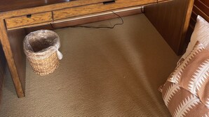 Un bureau en bois avec un téléviseur à écran plat, une lampe et une corbeille à papier.