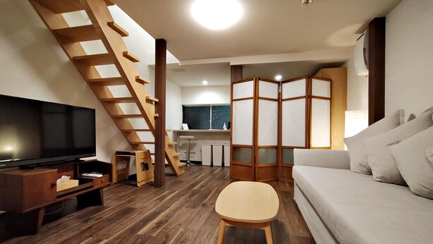Ein Wohnzimmer mit Fernseher, Holztreppe und einer Couch.