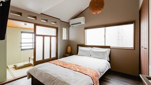 Ein Schlafzimmer mit Bett, Fenster, Klimaanlage und einer Pendelleuchte.