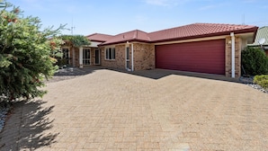 Une maison à deux étages, avec un toit recouvert de tuiles rouges, une façade en briques et un garage fermé.