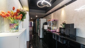 Eine moderne Küche mit Marmorarbeitsplatte, einem Kühlschrank, einer Mikrowelle und einem Automaten.