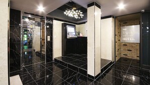 Eine moderne Hotelhalle mit Marmorboden, einer digitalen Kiosk und einem Schild für das Terracan Boutique Hotel.
