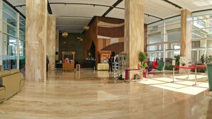 Een ruime lobby met hoge plafonds, grote ramen en een centraal gelegen receptie.
