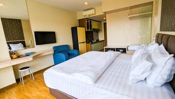 Una habitación de hotel con una cama grande, un escritorio, una silla, un televisor y un minibar.