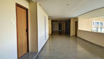 A corridor with a wooden door, a light switch, and a security camera.