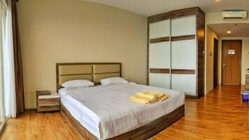 A hotel room with a large bed, a nightstand, a wardrobe, and a bathroom visible in the background.
