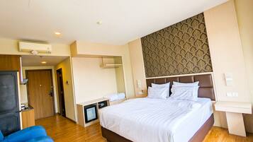 A hotel room with a large bed, a TV, a desk, and a mirror.
