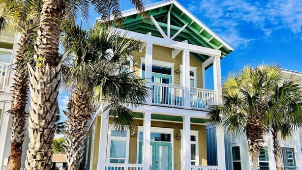 A two-story building with a balcony, surrounded by palm trees.