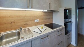 Een moderne keuken met een houten achterwand, roestvrijstalen apparatuur en een inbouwoven.