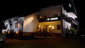 Un hotel con un letrero que dice 'HOTEL' sobre la entrada, una escalera que conduce a la puerta principal y un balcón en el piso superior.