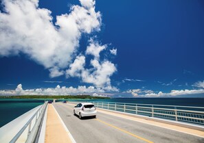 Un puente con una carretera, un coche y vistas al océano y al cielo.