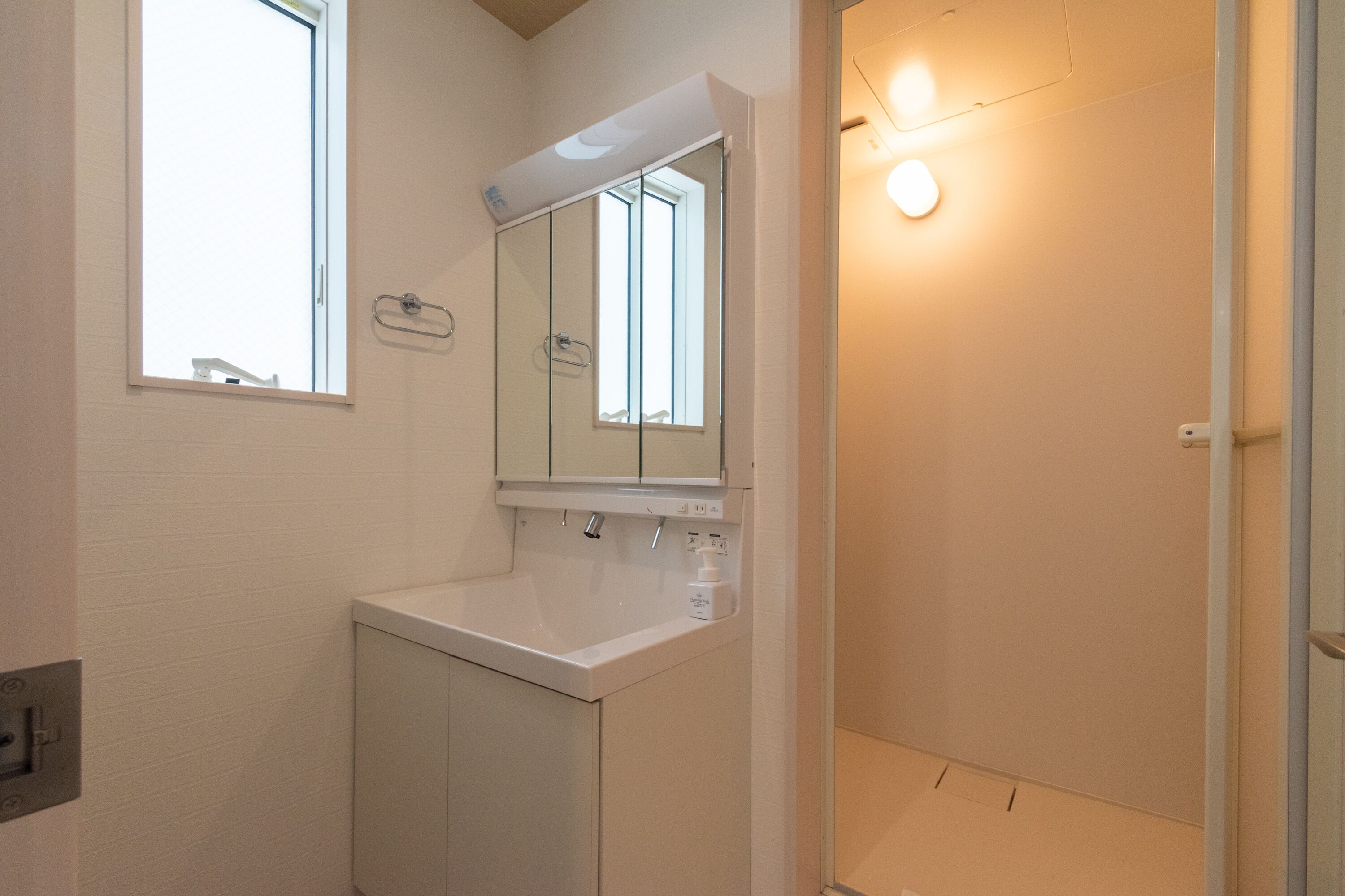 Un baño con lavamanos blanco, espejo y ducha.