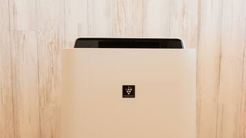 A white SHARP air purifier in a room with wooden flooring and a wooden wall.