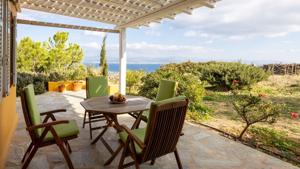 An outdoor patio with a pergola, stone flooring, wooden furniture, and potted plants. - Bralos Villa - Paros - Near Naousa, spectacular sea views, 2 bedrooms, privacy (Paros)
