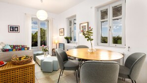 A well-lit room with a round wooden table, grey upholstered chairs, a wicker basket, and a vase with flowers. - Bralos Villa - Paros - Near Naousa, spectacular sea views, 2 bedrooms, privacy (Paros)