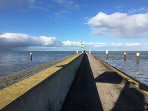 A concrete pier extending into calm waters with a clear sky and a few clouds.