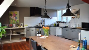 Une cuisine moderne avec une table à manger en bois, deux lampes suspendues et divers appareils de cuisine.
