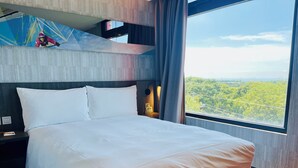 A modern hotel room with a large bed, a nightstand, a lamp, and a view of greenery outside. - Lihpao Resort - T11T12 Hotel (Taichung)