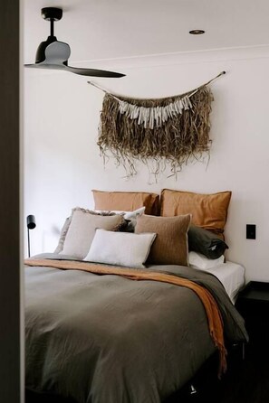 Un lit avec une couverture verte, plusieurs oreillers et un élément décoratif fixé au mur.