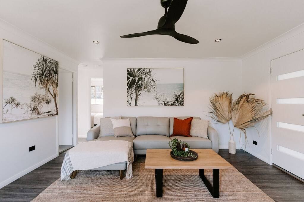 A modern living room with a grey sofa, a wooden coffee table, and artwork on the walls.