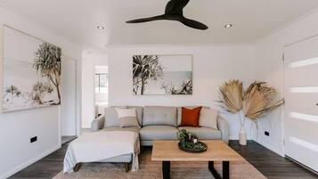 A modern living room with a grey sofa, a wooden coffee table, and artwork on the walls.