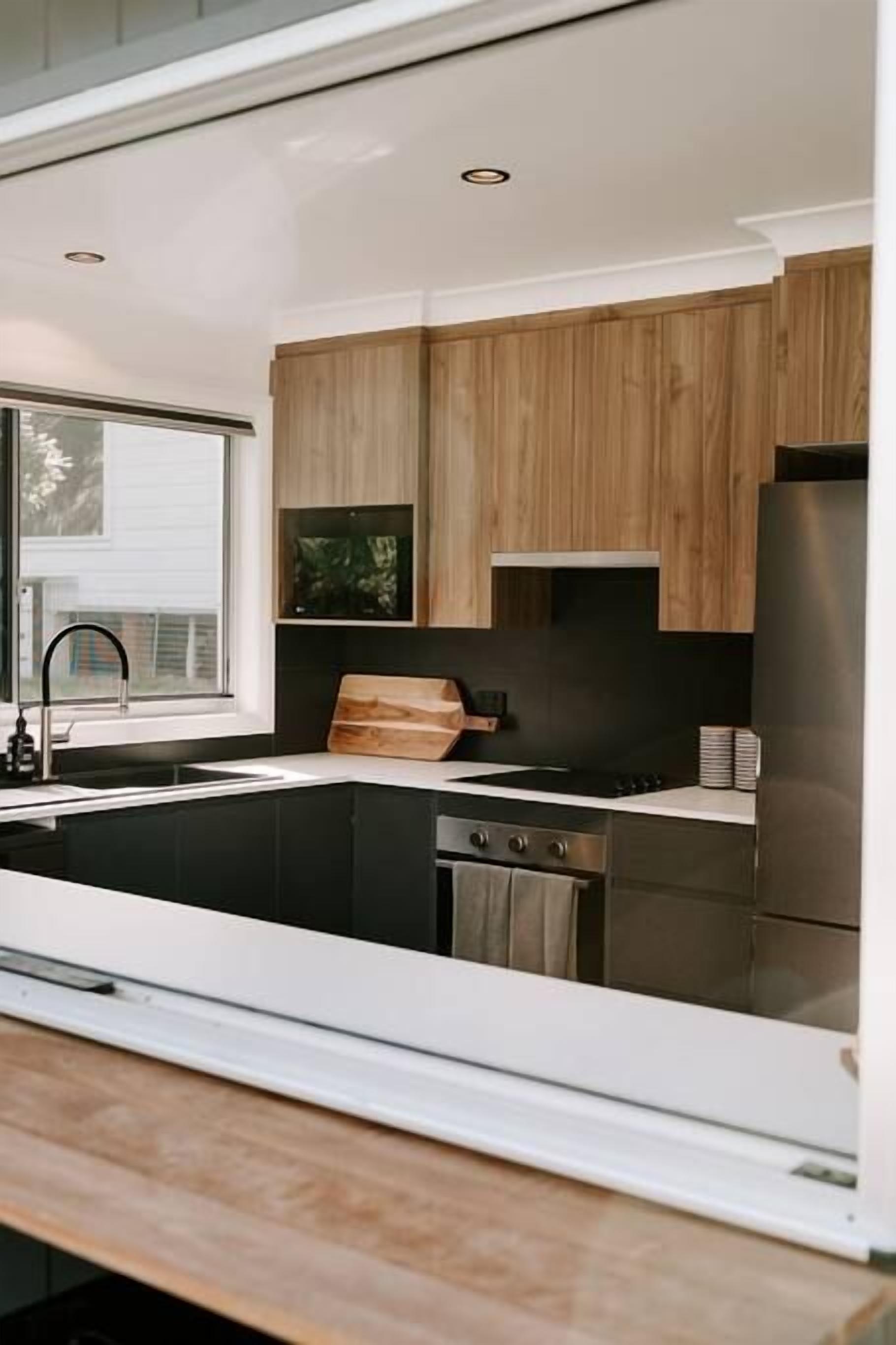 A modern kitchen with wooden cabinets, a stainless steel refrigerator, and a built-in oven.