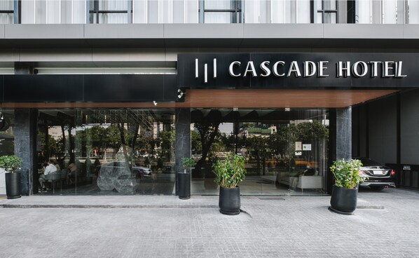 Exterior de l'Hotel Cascade, amb façana moderna, grans finestres de vidre i plantes en testos a l'entrada.