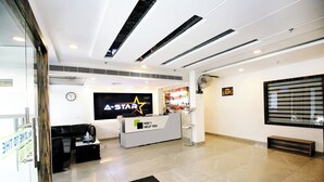 A modern reception area with a reception desk, a clock, and a large screen displaying 'A-STAR' branding. - Hotel A Star - 50 Meter from Golden temple (Amritsar)