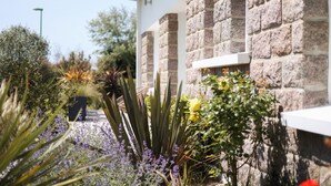 A stone building with a white exterior and a garden with various plants and flowers. - Villa Espérance, a stone's throw from Barneville beach, rated 3 ***. (Saint-Jean-de-la-Rivière)