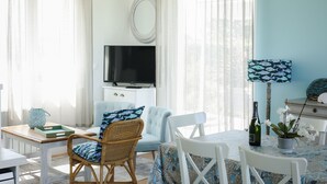 A room with a television, wicker chairs, a dining table, and a potted plant. - Villa Espérance, a stone's throw from Barneville beach, rated 3 ***. (Saint-Jean-de-la-Rivière)