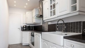 A modern kitchen with white cabinetry, a black countertop, and a tiled backsplash.