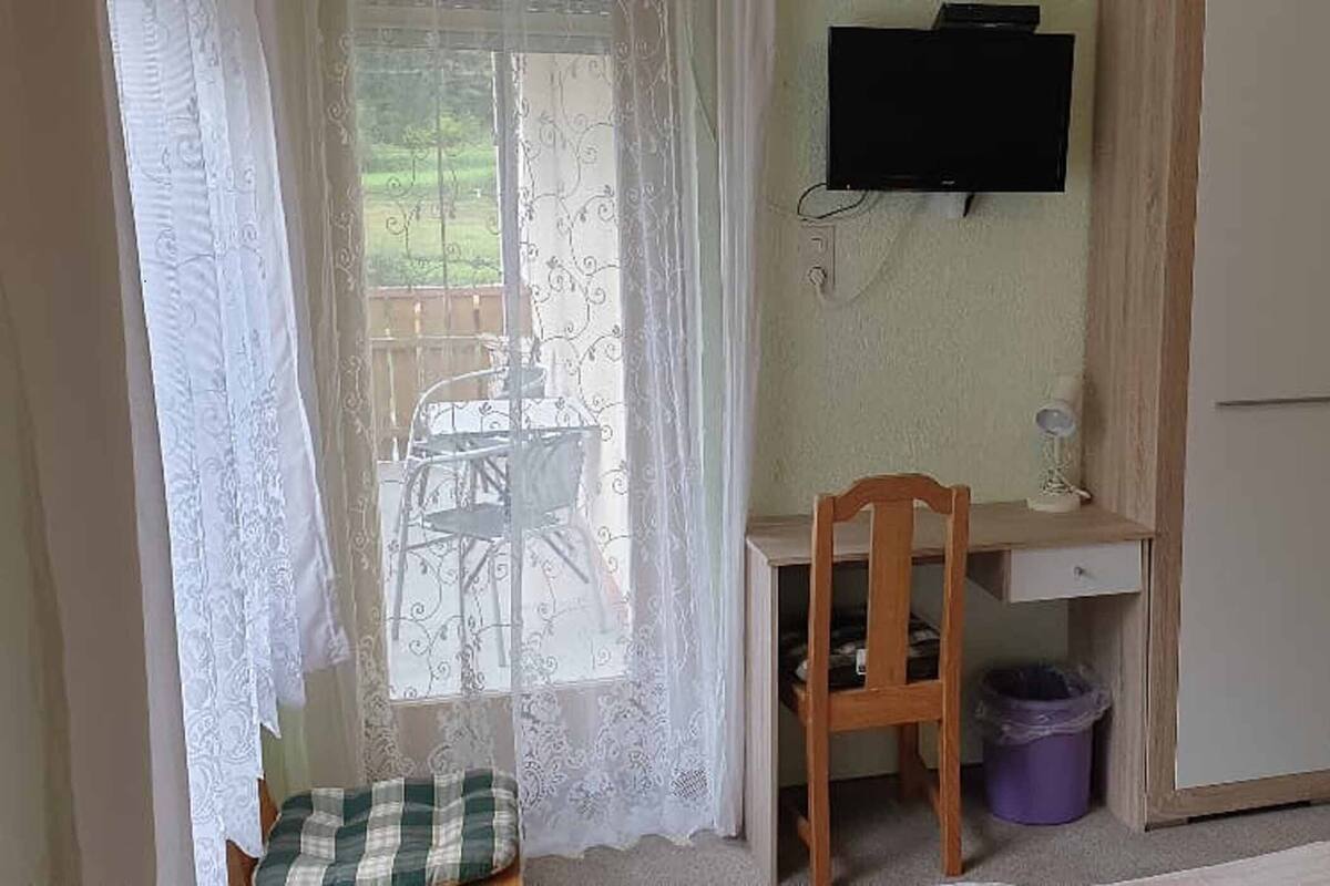 A bedroom with a bed, a desk, a chair, a TV, and a wardrobe.