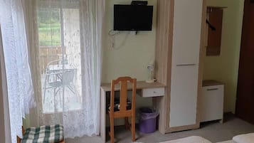 Une chambre à coucher comprenant un lit, un bureau, une chaise, un téléviseur et une armoire.